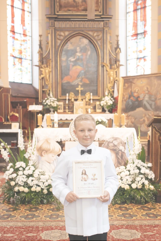 Portret chłopca w albie komunijnej w kościele przed ołtarzem