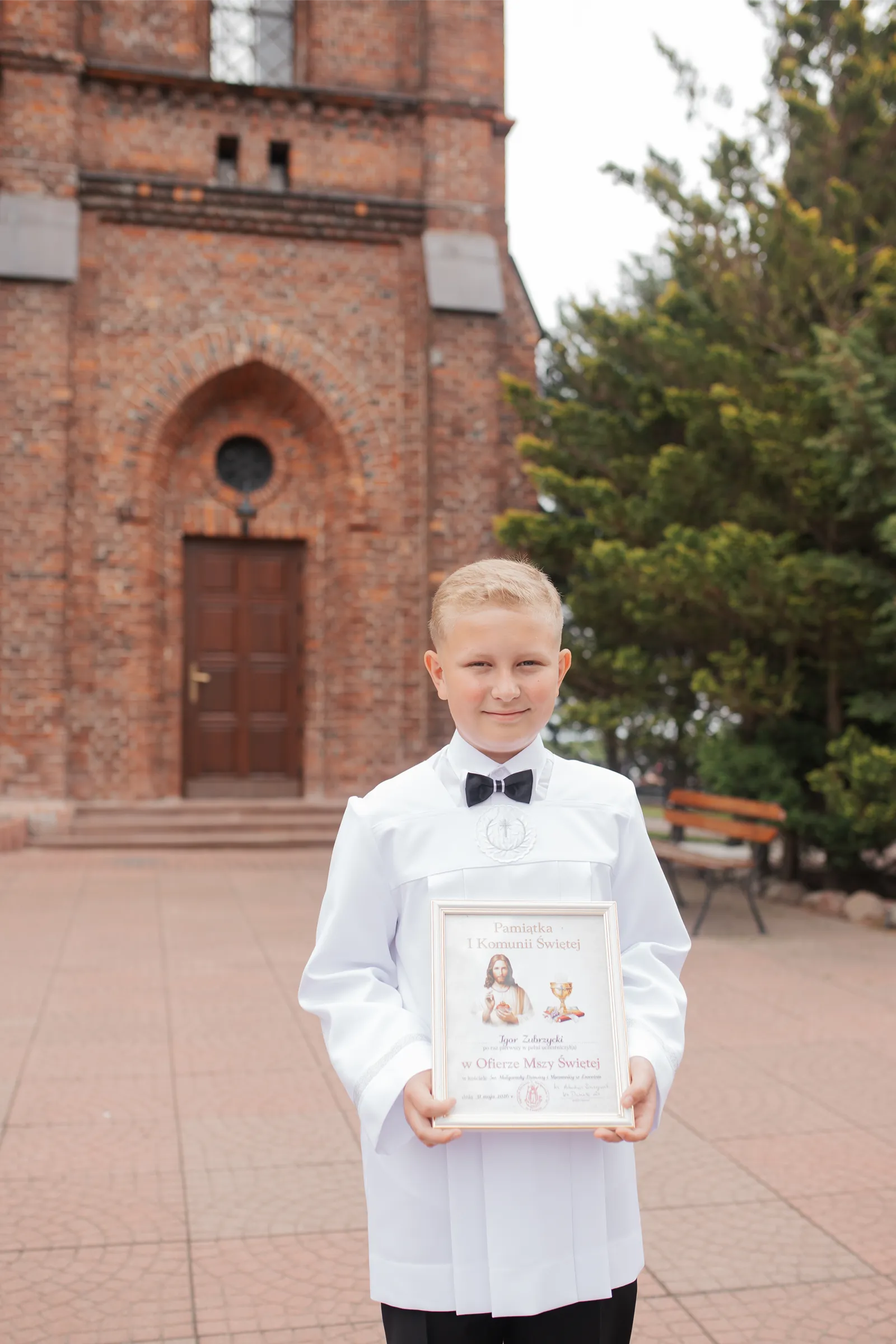 Chłopiec z obrazkiem komunijnym przed kościołem w Nowym Dworze Mazowieckim – fotograf na komunię