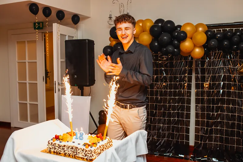 Mężczyzna przy torcie z zimnymi ogniami i balonami – reportaż z przyjęcia urodzinowego