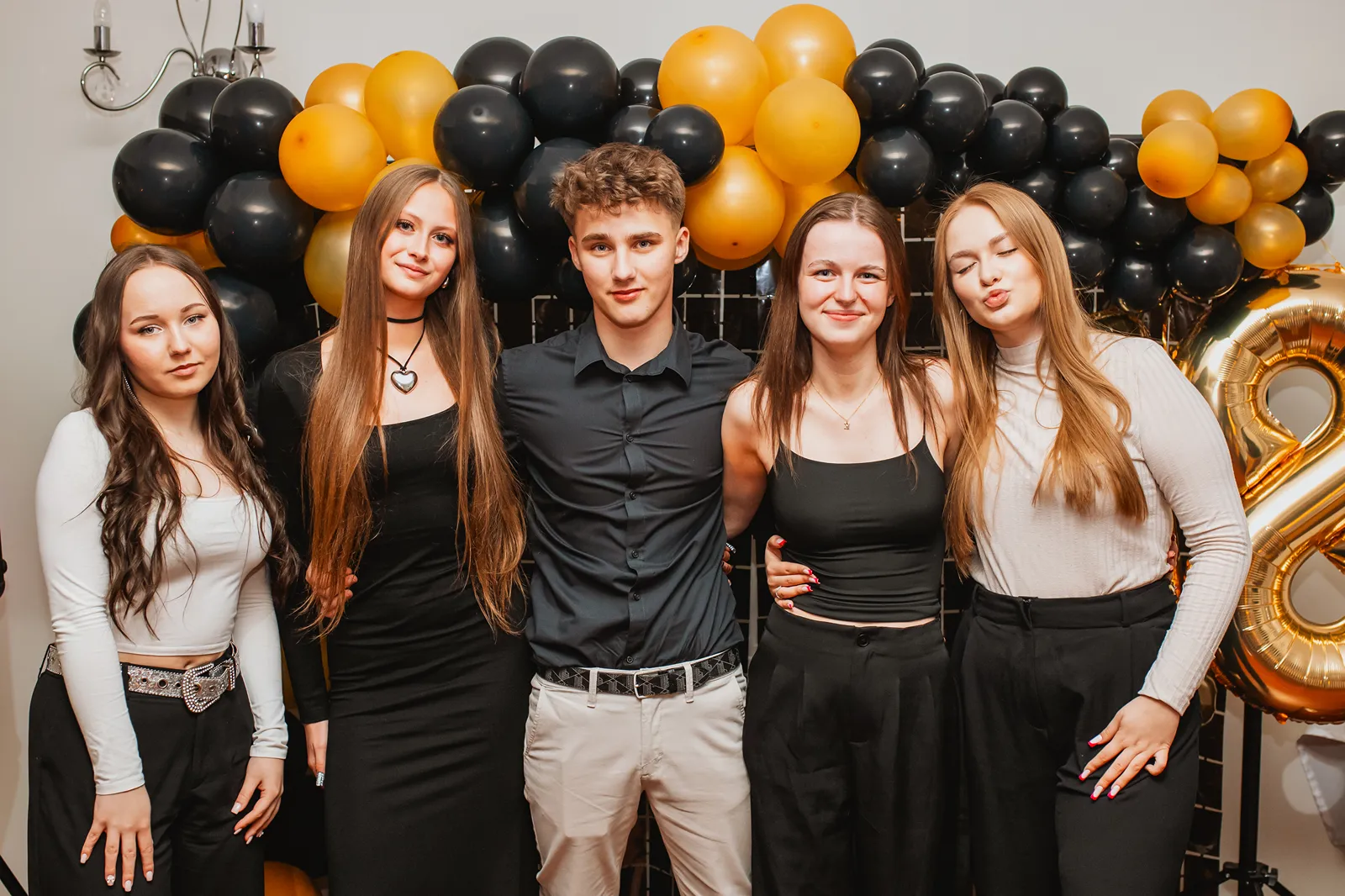 Wesoła grupa pozująca w zabawnych pozach na sali podczas imprezy okolicznościowej