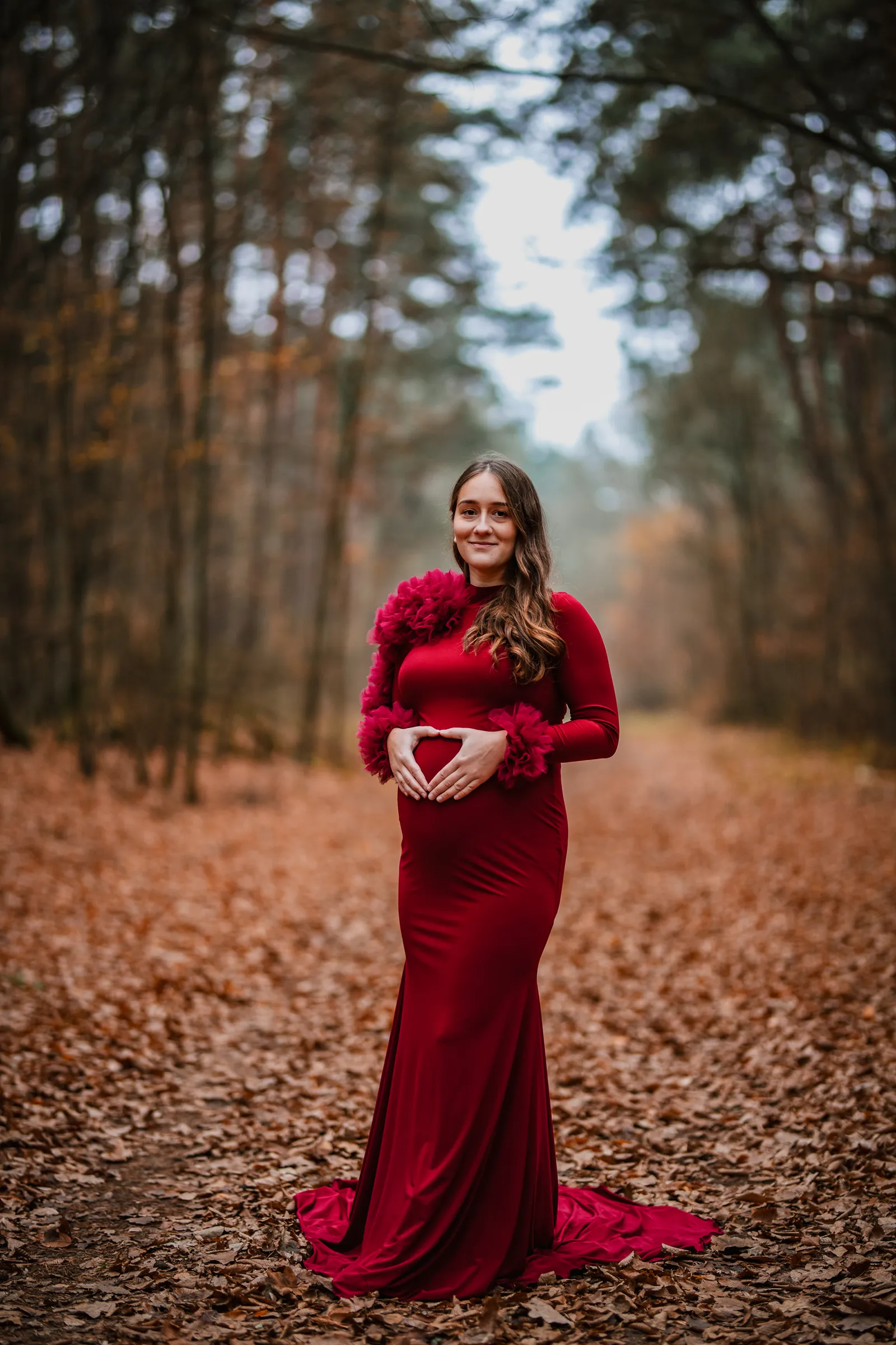 Kobiecy portret ciążowy w czerwonej sukience - sesja brzuszkowa w plenerze