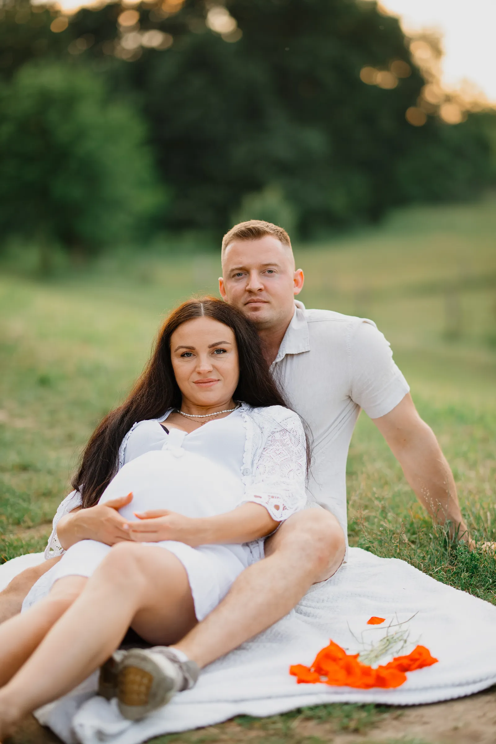Piknikowa sesja ciążowa na kocu - kadry na trawie w plenerze