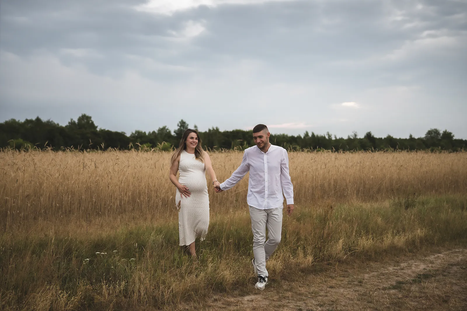 Spacer polną ścieżką we dwoje podczas sesji ciążowej