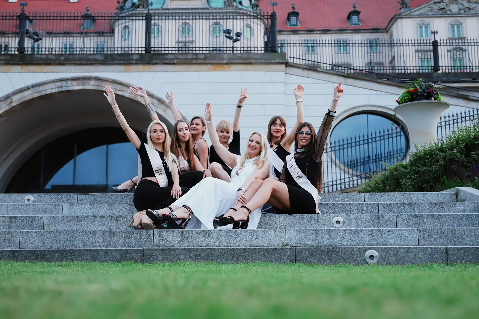 Dziewczyny siedzące na schodach z podniesionymi rękami w Warszawie
